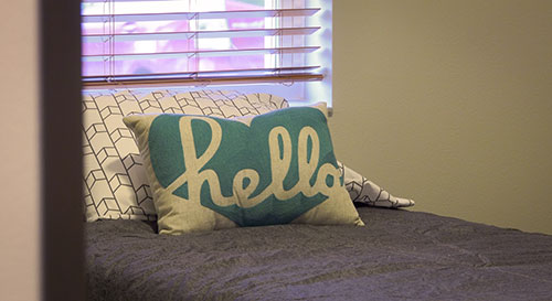 Bed with a turquoise hello pillow