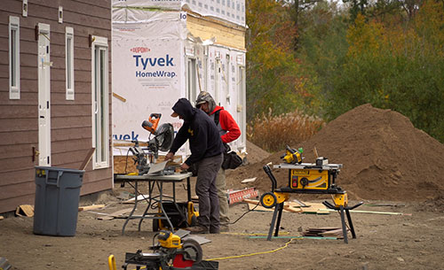Men using saw in front of homes under construction