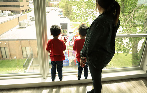 Woman and two children looking out window